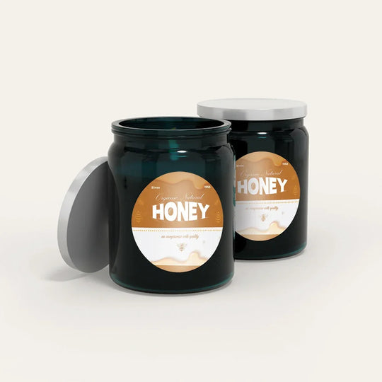 Two dark teal glass jars of organic natural honey with silver lids.