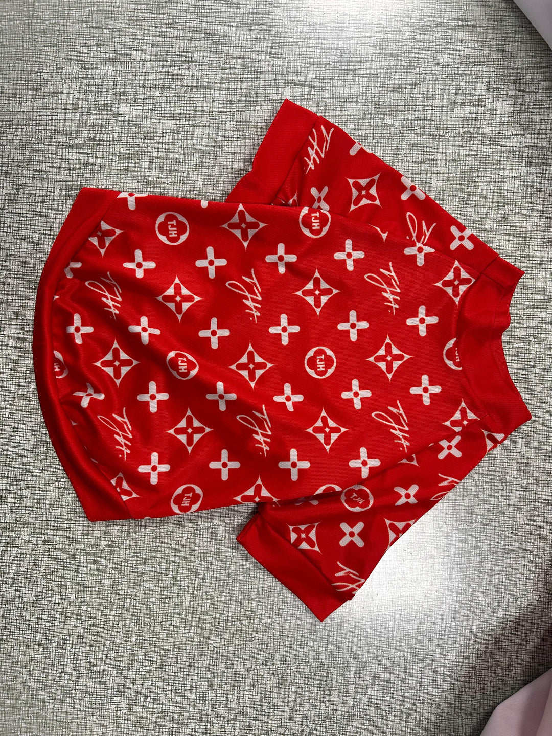 Red custom apparel shorts with white monogram patterns on a grey textured background