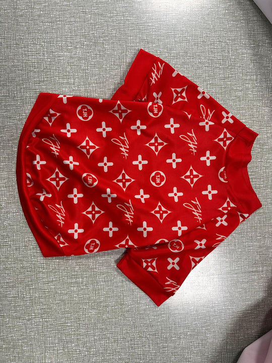 Red custom apparel shorts with white monogram patterns on a grey textured background