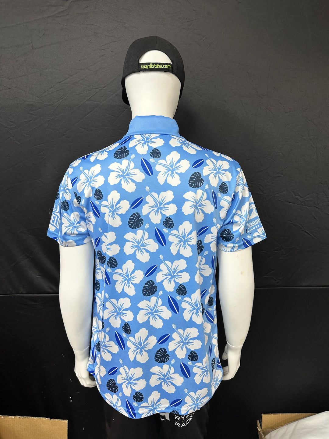 Rear view of a blue short-sleeve button-down shirt with a white and navy floral pattern.