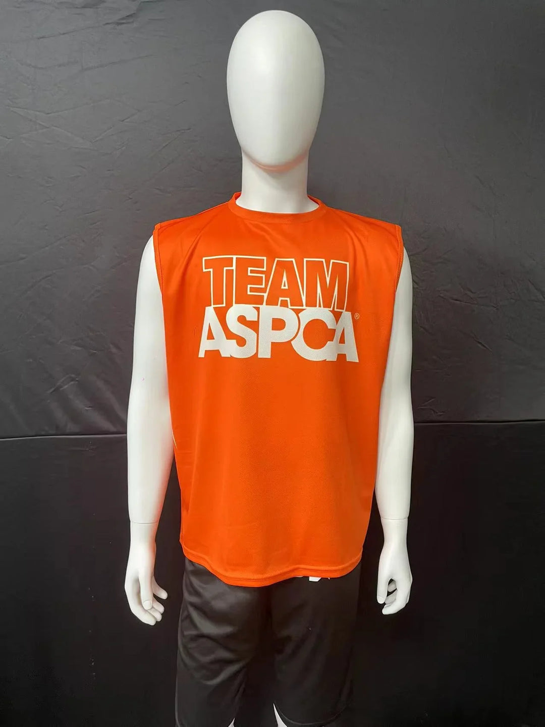 Orange sleeveless athletic shirt with 'TEAM ASPCA' printed in white on a mannequin.
