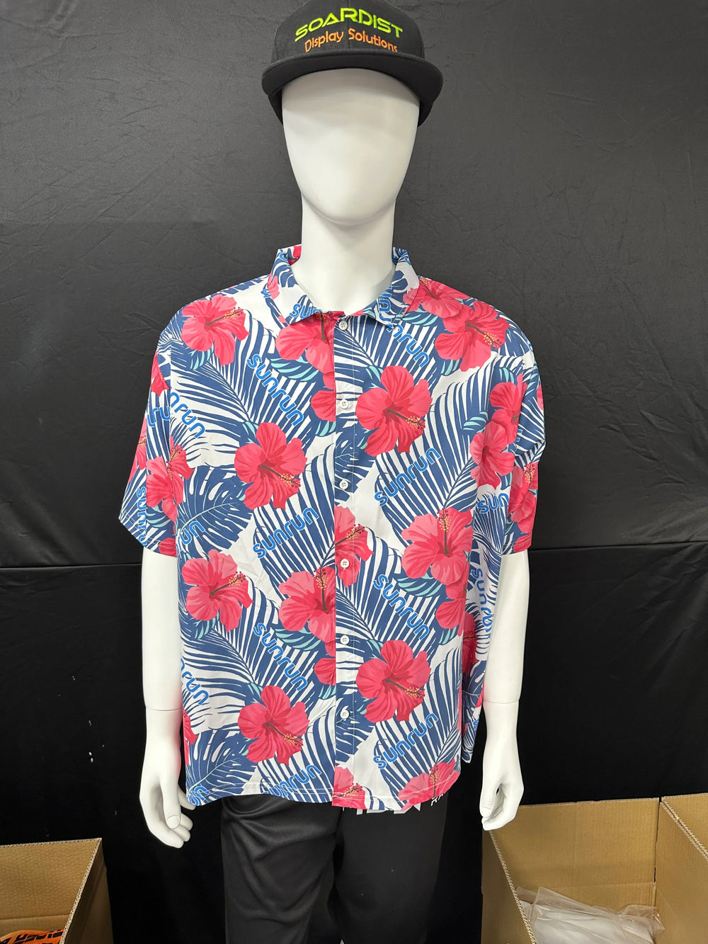 Mannequin wearing a white short-sleeve Hawaiian shirt with red hibiscus flowers and blue leaves.