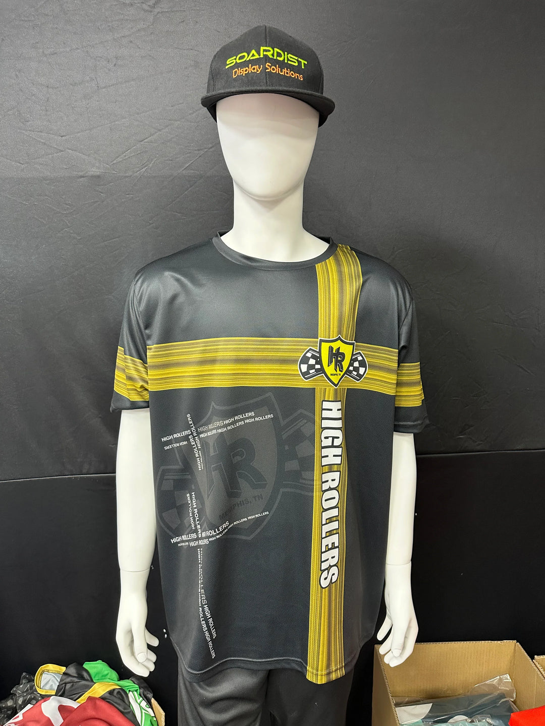 Custom black and yellow High Rollers racing jersey and matching cap on a mannequin.