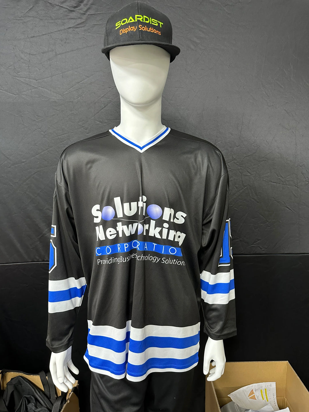 Mannequin wearing a custom black and blue hockey jersey with company branding