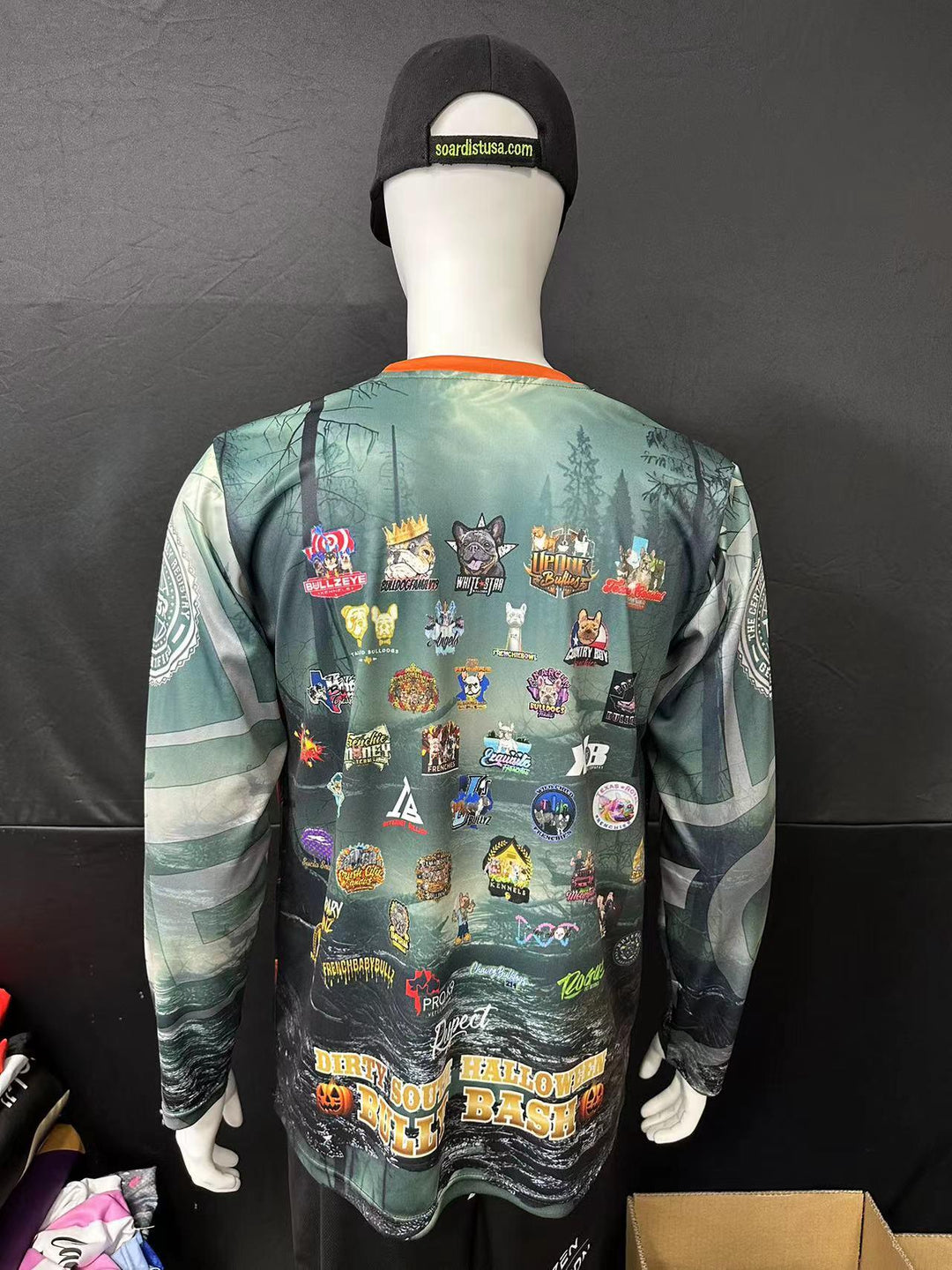 Back view of a custom long sleeve jersey with forest graphics and multiple colorful patches.
