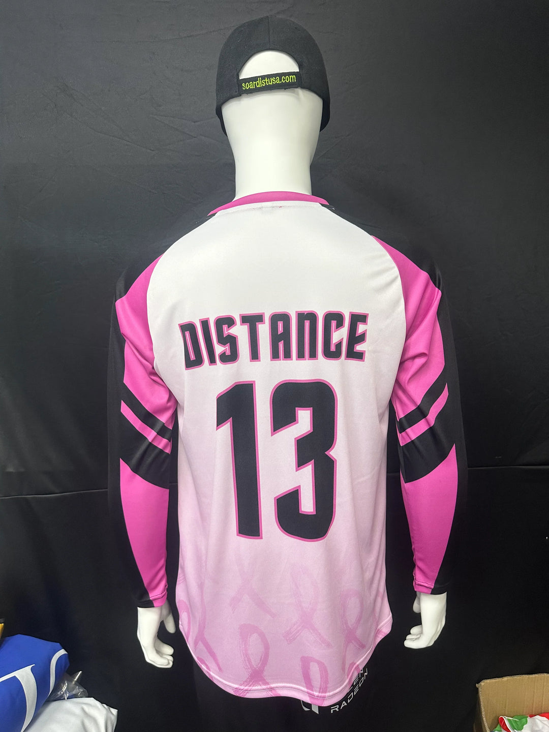 Back view of a custom pink and white long sleeve athletic jersey with 'DISTANCE 13' printed on it.