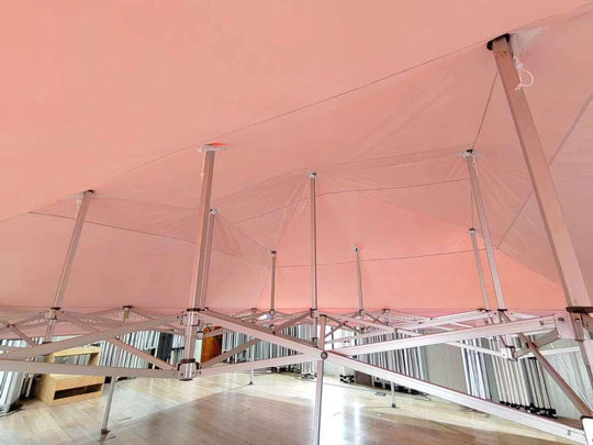Interior view of a large pink custom event tent with a silver metal frame structure