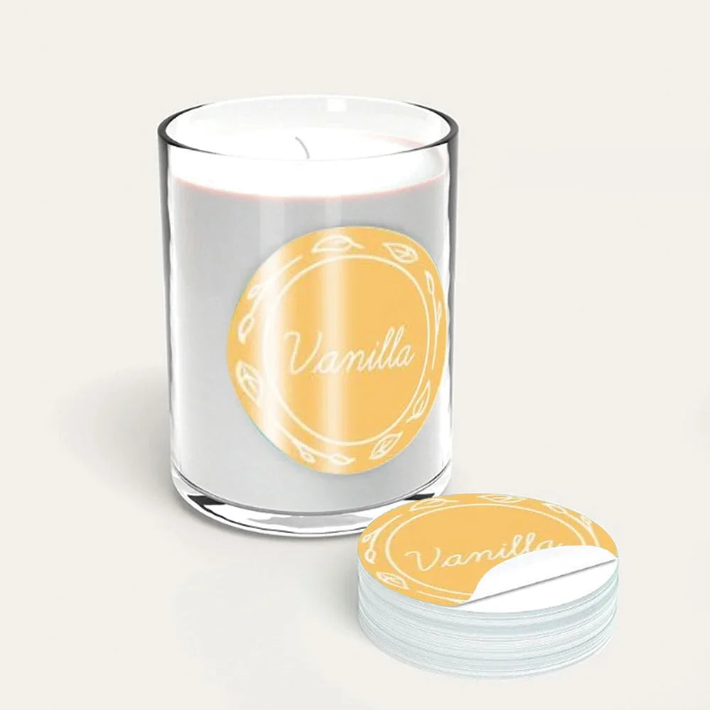 Custom circular yellow vanilla scent labels on a glass candle jar and a sticker roll.