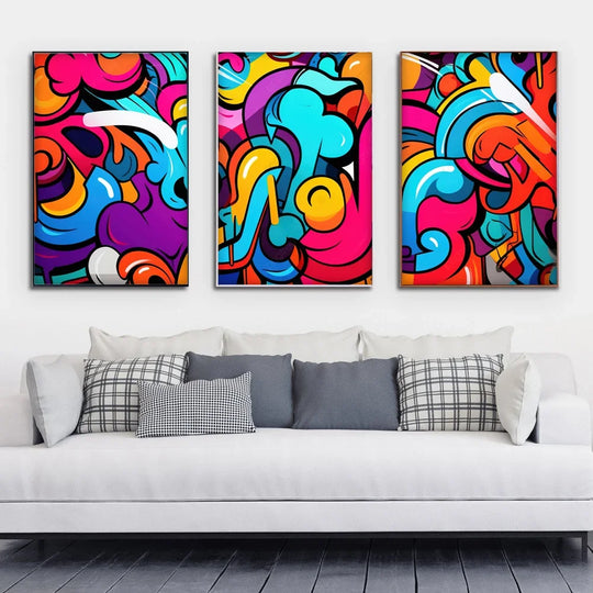 Three colorful abstract graffiti art canvases hanging above a white modern sofa.