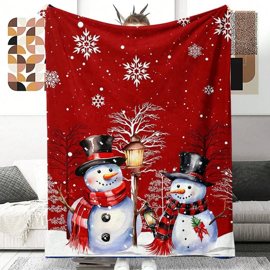 Red winter blanket featuring two snowmen with scarves and hats under snowflakes