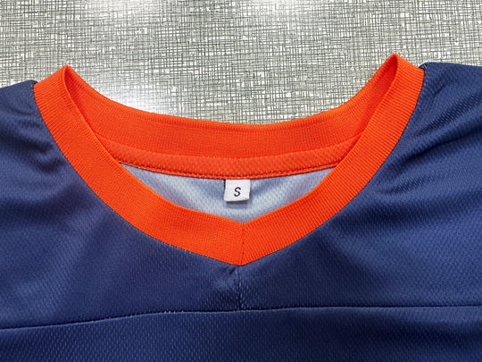 Close-up of the neckline of a navy blue sports apparel jersey with orange trim and size S tag.