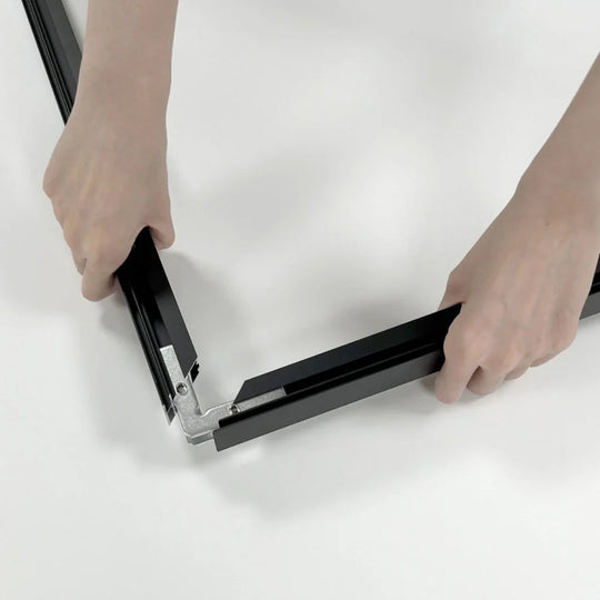 Hands assembling black aluminum frame components for a custom tent or banner stand.