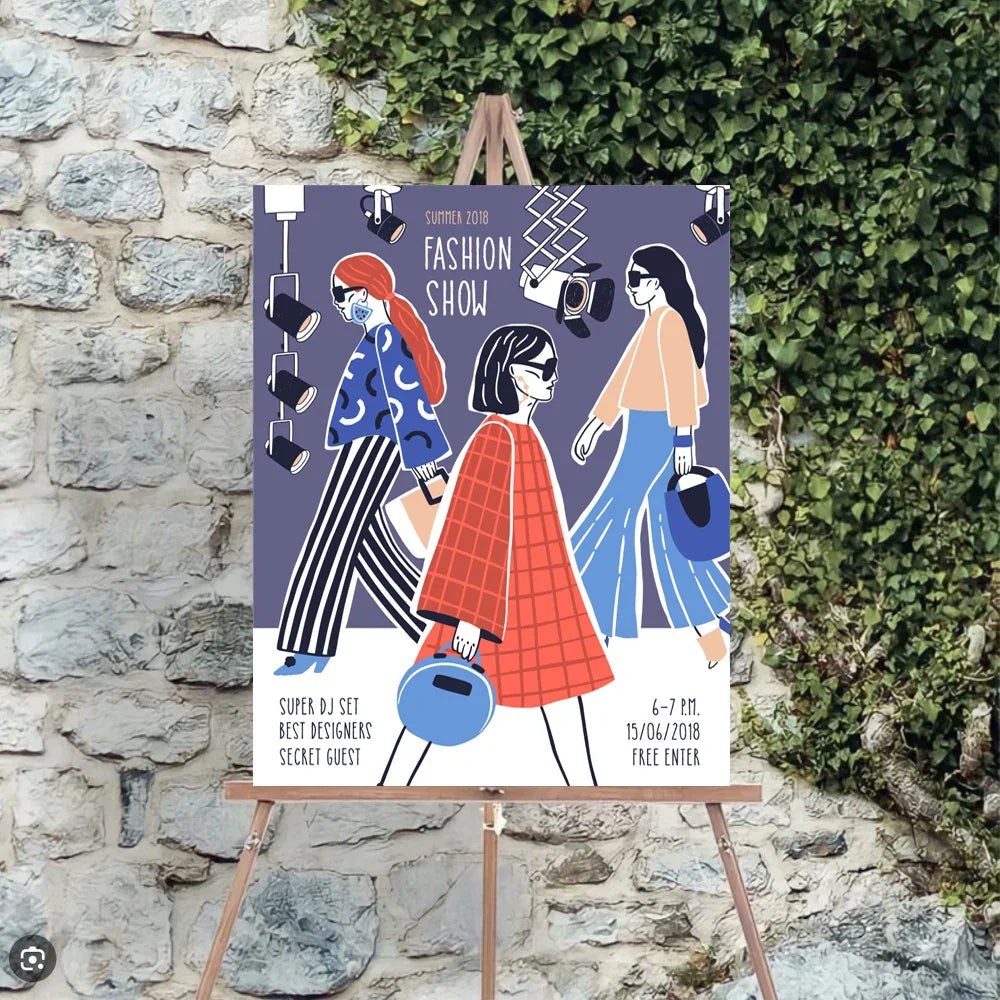 A custom printed event banner for a fashion show displayed on a wooden easel against a stone wall.