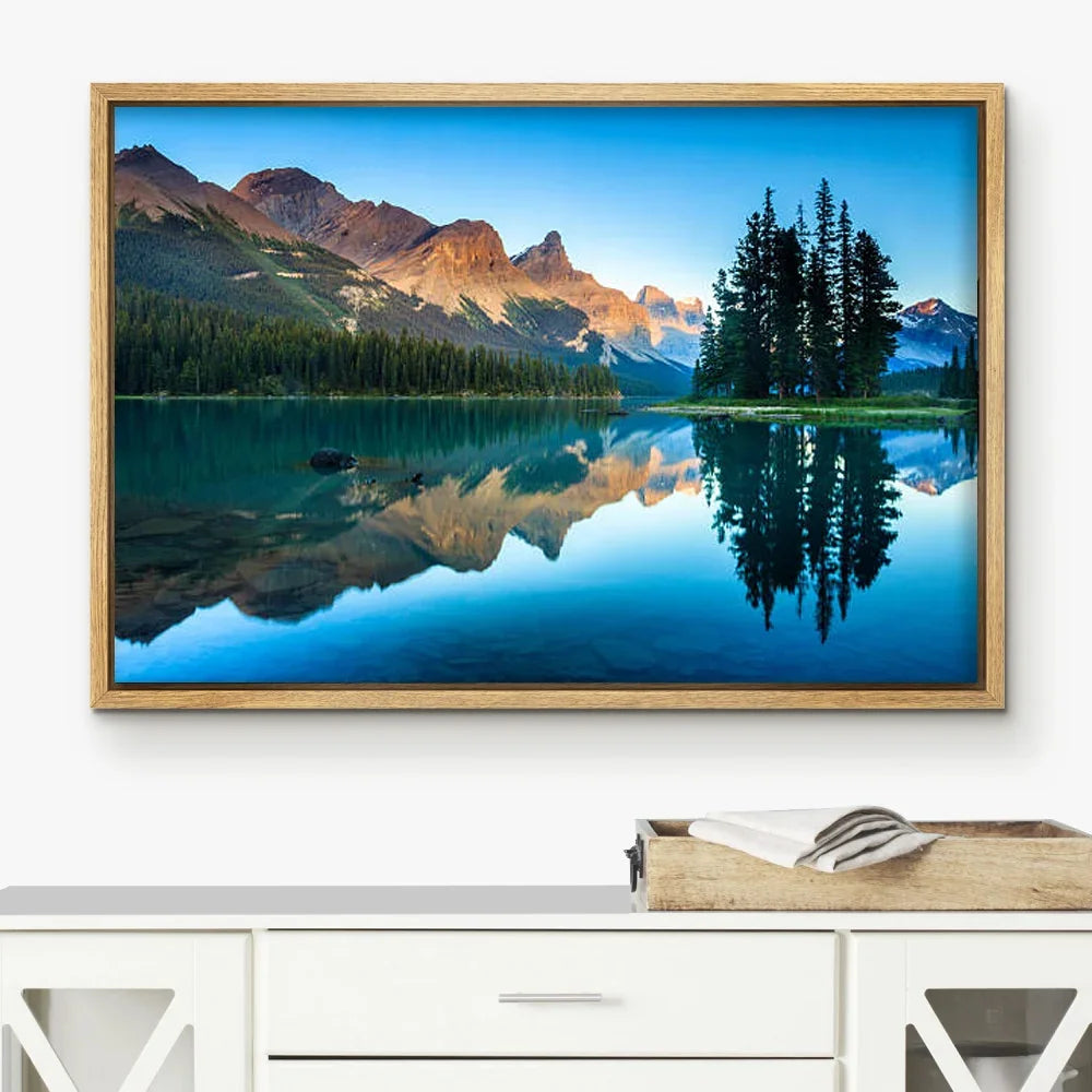 Framed landscape wall art featuring a mountain range and pine trees reflecting in a calm lake