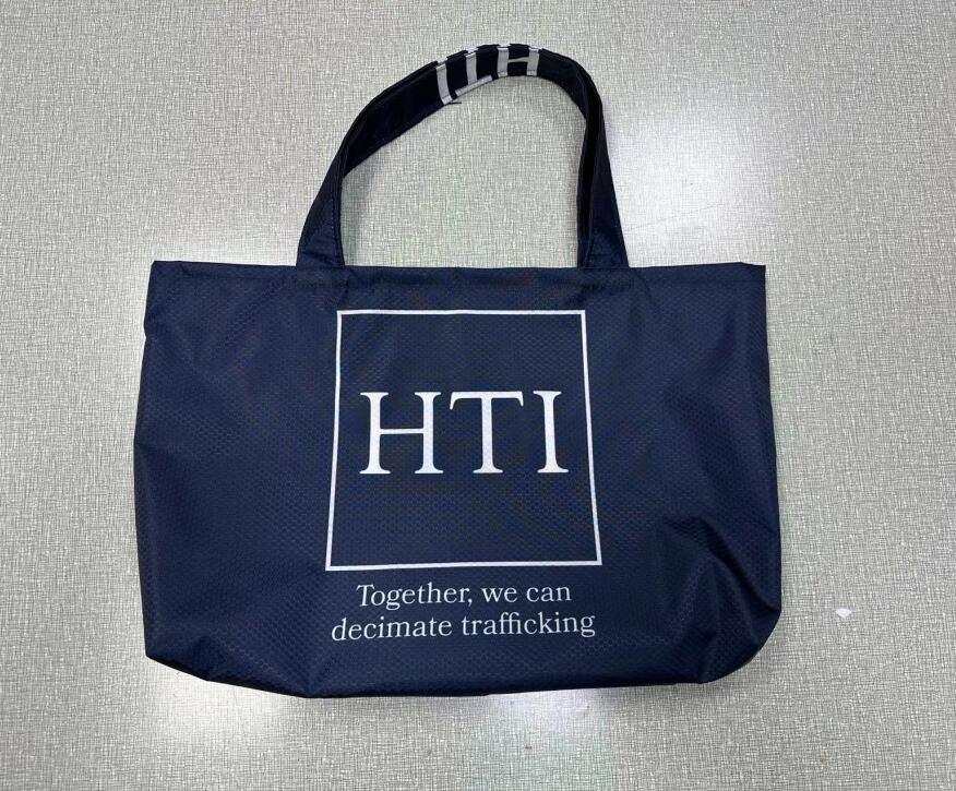 Navy blue custom tote bag with HTI logo and anti-trafficking slogan