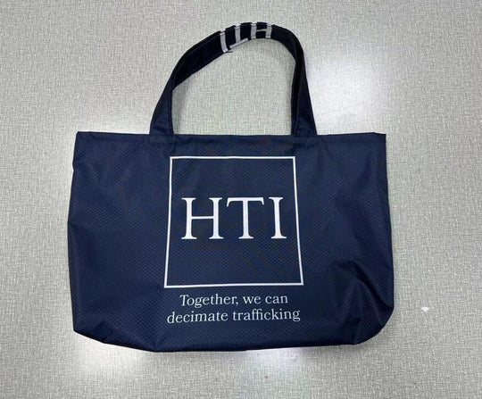 Navy blue custom tote bag with HTI logo and anti-trafficking slogan