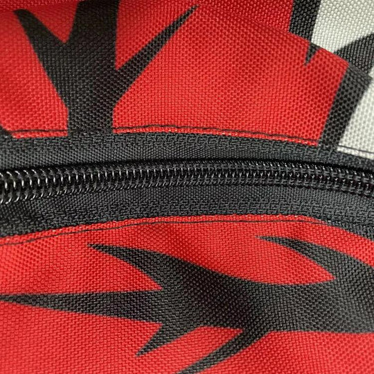 Close-up of a red and black printed fabric bag with a black zipper closure.