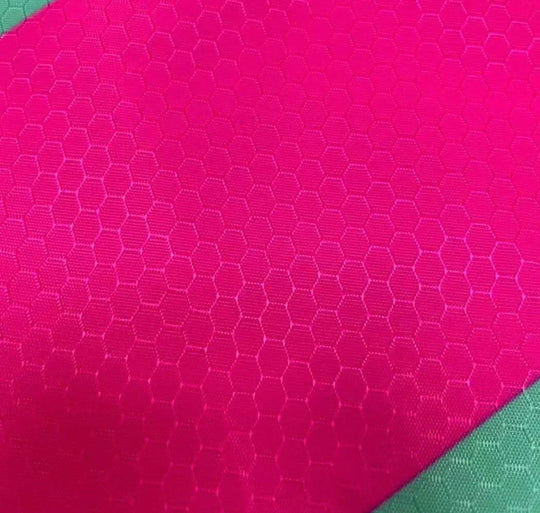 Close-up of hot pink hexagonal honeycomb pattern synthetic fabric