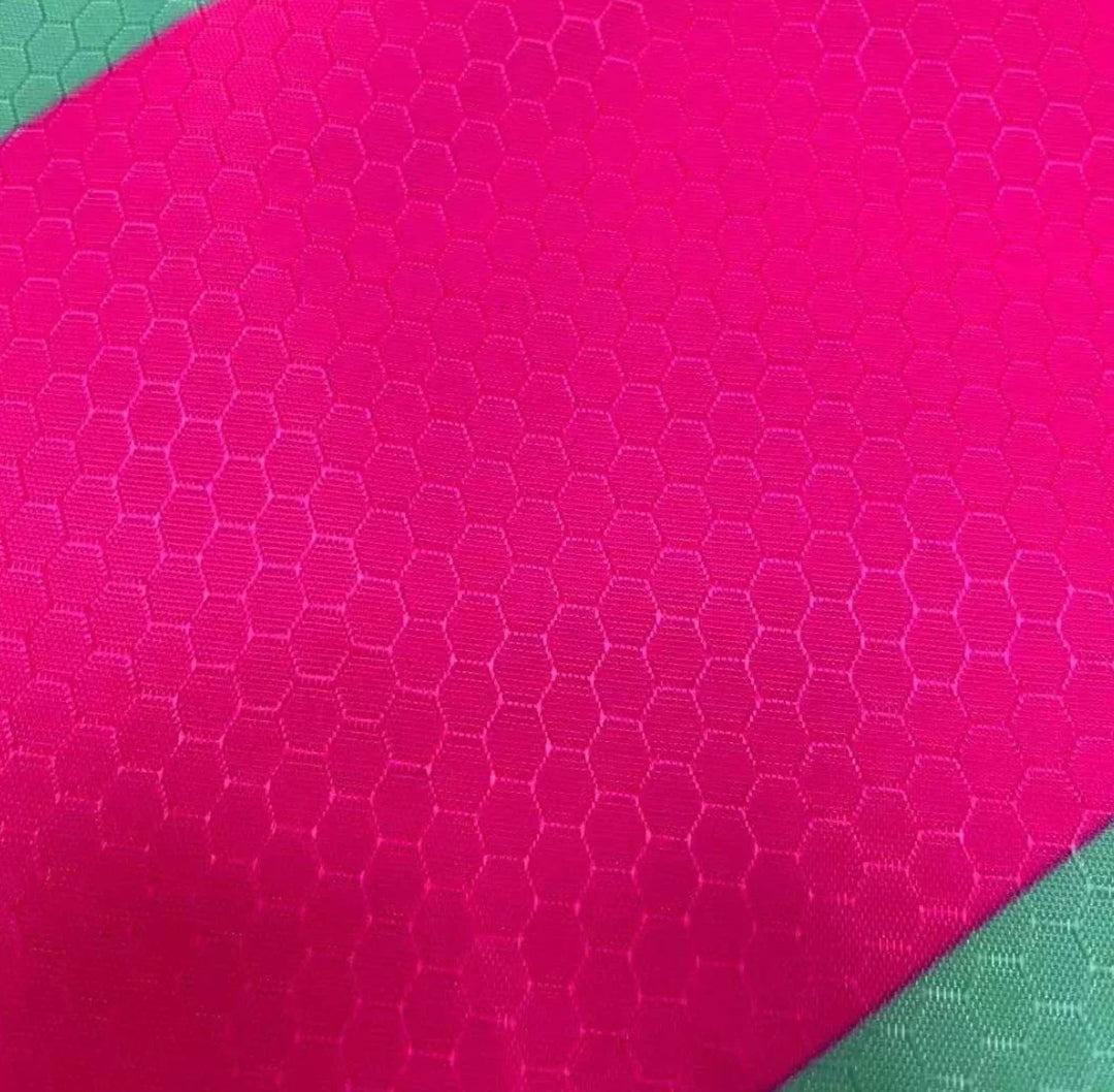 Close-up of bright pink honeycomb textured performance fabric for custom apparel.
