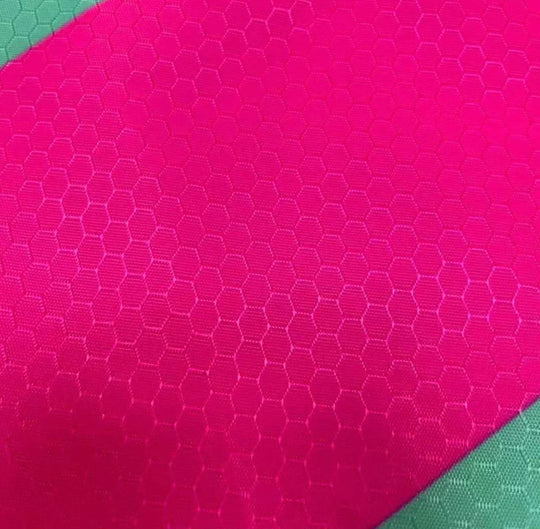 Close-up of bright pink honeycomb textured performance fabric for custom apparel.